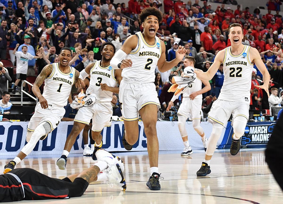 Michigan's Jordan Poole runs from teammates.